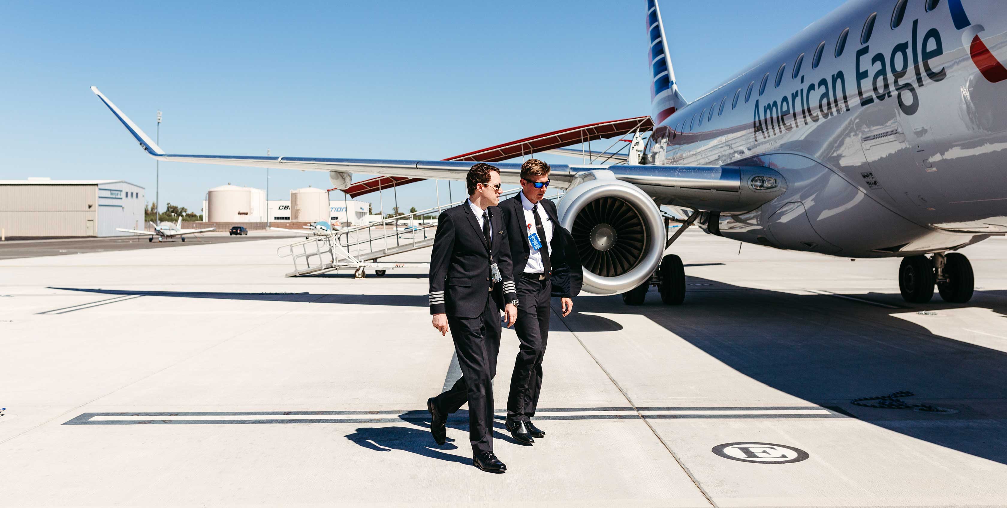 Two airlines pilots walking near an American Eagle ERJ at IWA Training Center