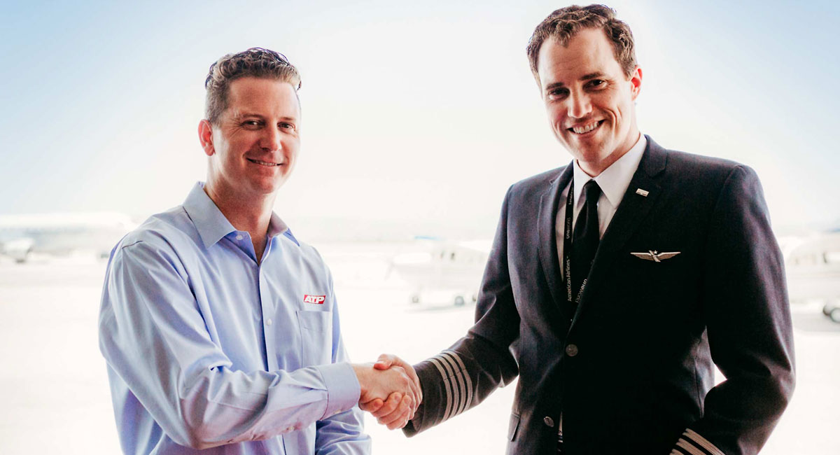 Student pilot shaking hands with airline representative over contract at ATP Flight School